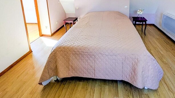 A bedroom with a sloped ceiling, a bed, a small table, and a chair.