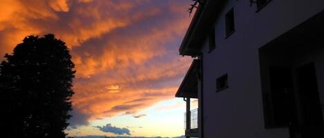 A building with a balcony, a tree, and a sunset sky.