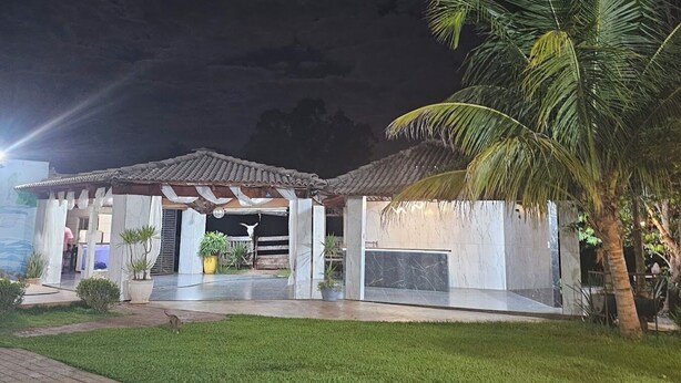 A modern building with a covered patio, palm trees, and a well-maintained lawn.