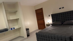 Une chambre à coucher avec un lit, une armoire, une table de chevet et un miroir.