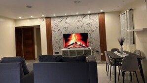 Un salon moderne doté d’un téléviseur à écran plat, d’une table à manger et de deux canapés.
