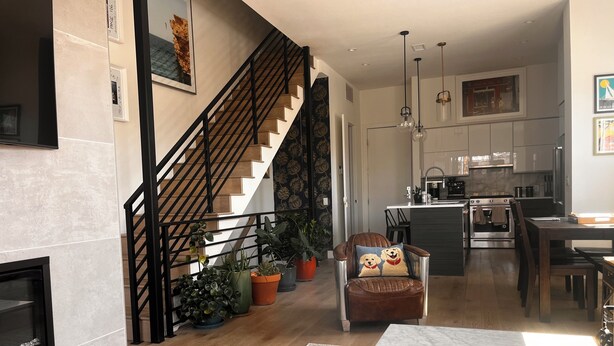 Een moderne woonkamer met een open haard, een trap, een eethoek en een keuken.
