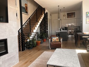 Una sala de estar moderna con chimenea, una escalera, un comedor y una cocina.