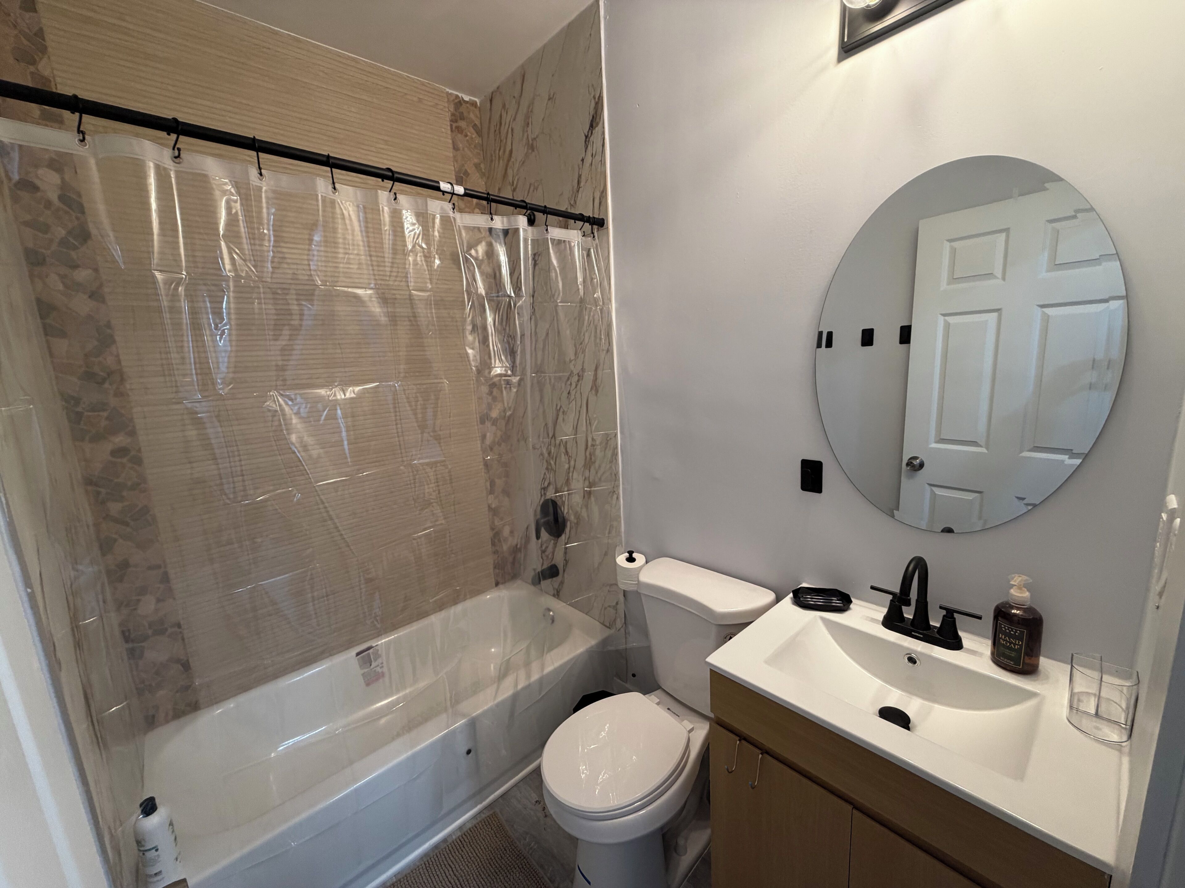 A bathroom with a bathtub, toilet, sink, and a mirror.