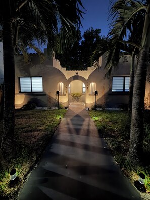 A pathway leading to a building with arched doorways and windows, surrounded by palm trees. - 2-bedroom townhome in fabulous Miami. (Miami)