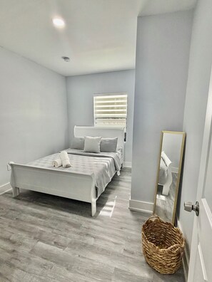 A bedroom with a bed, a mirror, and a window with blinds. - 2-bedroom townhome in fabulous Miami. (Miami)