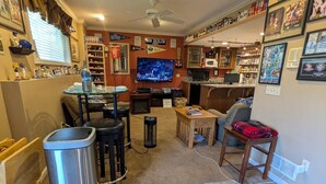 Un salon avec un téléviseur, une table basse, une cheminée et une bibliothèque.
