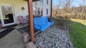 Un porche abrité avec un banc bleu, une porte et une fenêtre.