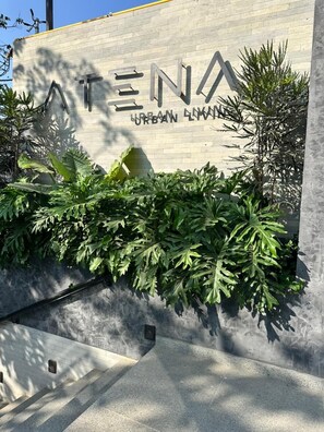 A building entrance with a sign reading 'ATENA URBAN LIVING' and a concrete wall with greenery. - Modern Apartment in Colonia Americana (Guadalajara)