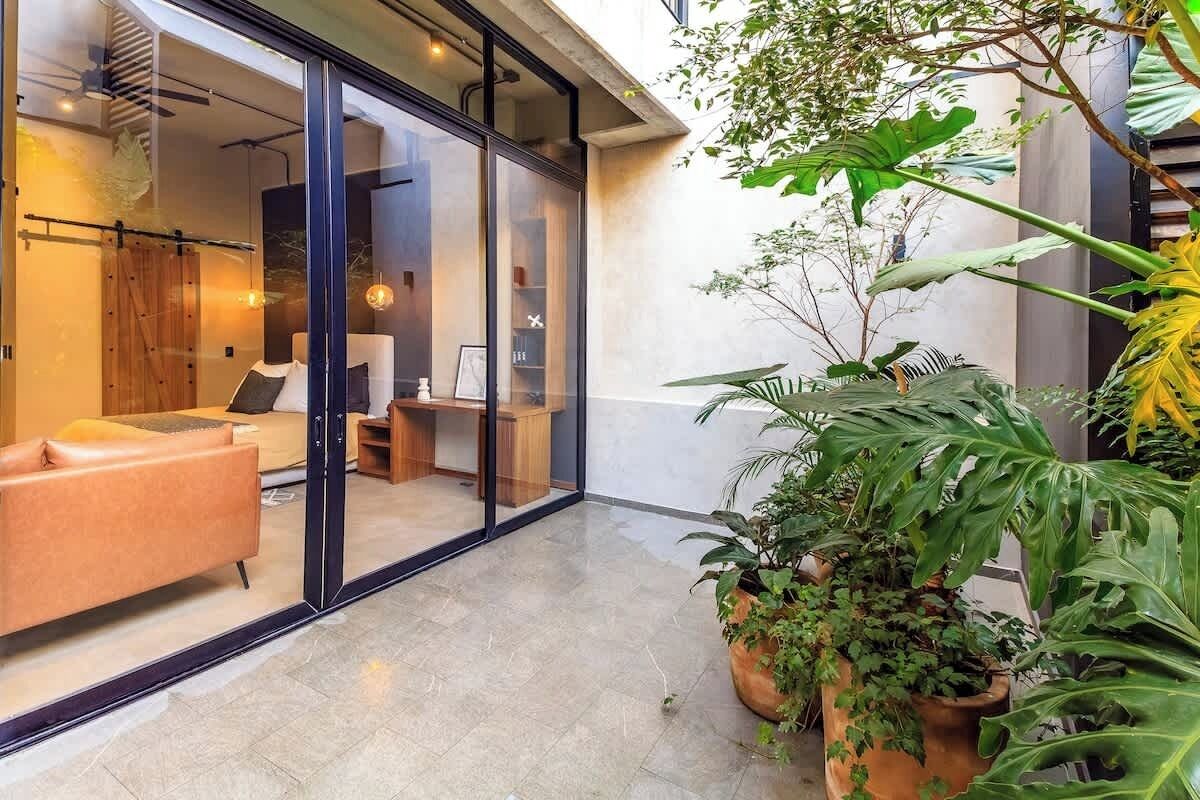 Un intérieur moderne avec une porte vitrée donnant sur un espace de vie, un canapé et un bureau en bois.
