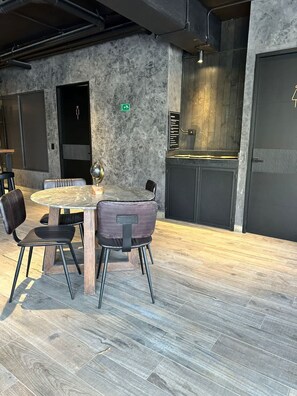 Un interno moderno con un tavolo rotondo, sedie, una zona bar e una porta con un'insegna.