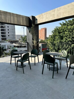 Una terrazza sul tetto con posti a sedere all'aperto, vista sulla città e una gru edile sullo sfondo.