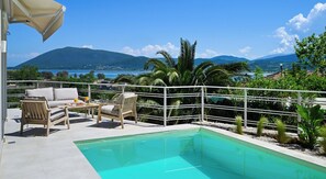 Un espace piscine offrant une vue sur la mer et les montagnes.