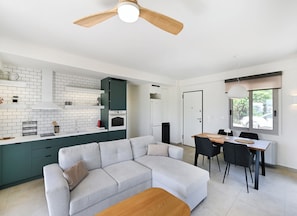 A modern kitchen with white and green cabinetry, a built-in oven, and a dining area with a table and chairs. - Maison D'Azur Lefkas Private Pool  (Lefkada)