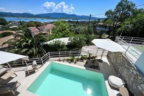 A swimming pool with lounge chairs, a stone wall, and a view of a lake and mountains. - Maison D'Azur Lefkas Private Pool  (Lefkada)