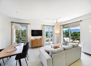 Un salon moderne comprenant un canapé, une table à manger, des chaises, un téléviseur et un balcon avec vue.