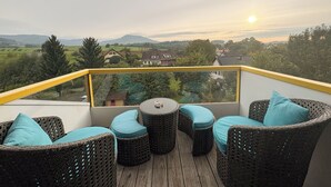 A balcony with wicker furniture and a view of houses and mountains.