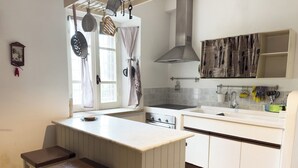 A kitchen with a central island, a stove, a sink, and a window with curtains. - Il Casale Sotto La Torre ***(Via del Colle 21, Torano di Borgorose) (Torano)