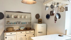 A kitchen with white cabinetry, a white Bosch refrigerator, hanging kitchen utensils, and a white countertop with a cake. - Il Casale Sotto La Torre ***(Via del Colle 21, Torano di Borgorose) (Torano)