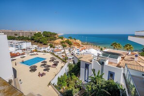 A resort with a swimming pool, sun loungers, and a view of the sea. - Beachside 1BR Stay for 4 – Easy Beach Access by Lift & Free Parking (Olhos de Água)