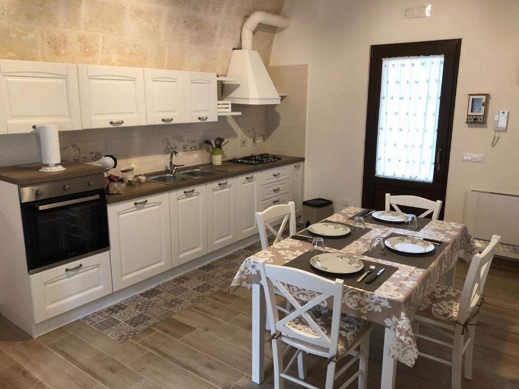 A kitchen with white cabinets, a gas stove, and a dining table set for four.