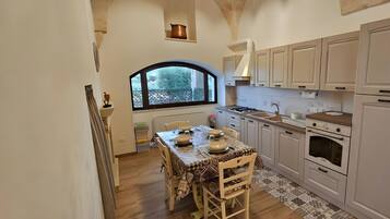 A kitchen with a dining table, cabinets, and a window.