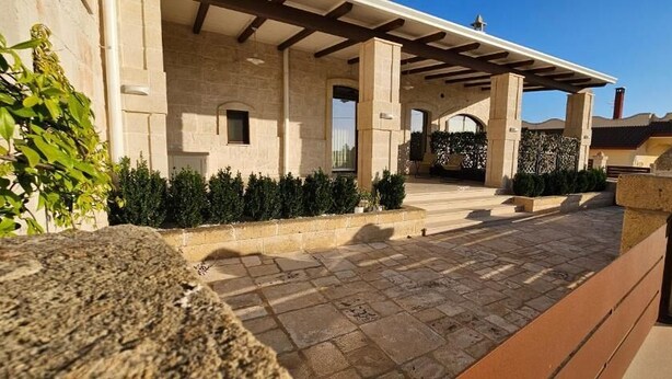 A stone building with a covered entrance, a paved pathway, and a stone bench. - Le Stelle di Nonna Anna (Monopoli)