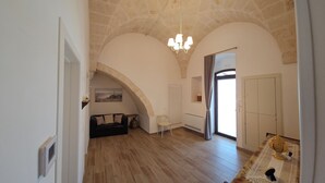 A spacious room with a stone ceiling, a chandelier, a sofa, a chair, and a wardrobe. - Le Stelle di Nonna Anna (Monopoli)