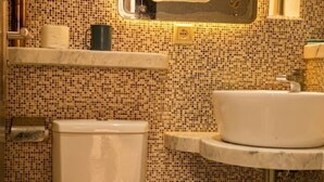 Un bagno con il water, un lavandino, uno specchio e una parete rivestita di piastrelle.