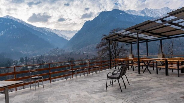 A terrace with tables and chairs, overlooking a mountainous landscape. - The himalayan Drift Cottage (Vashist)