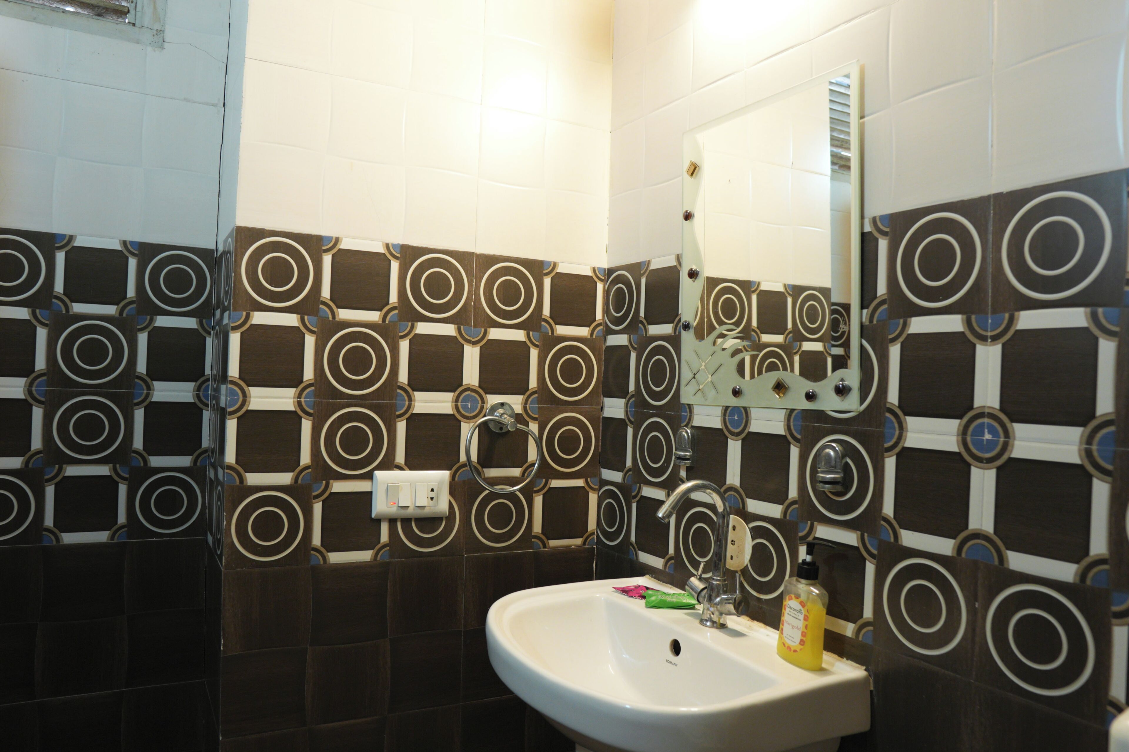 A bathroom with patterned tiles, a sink, and a mirror.