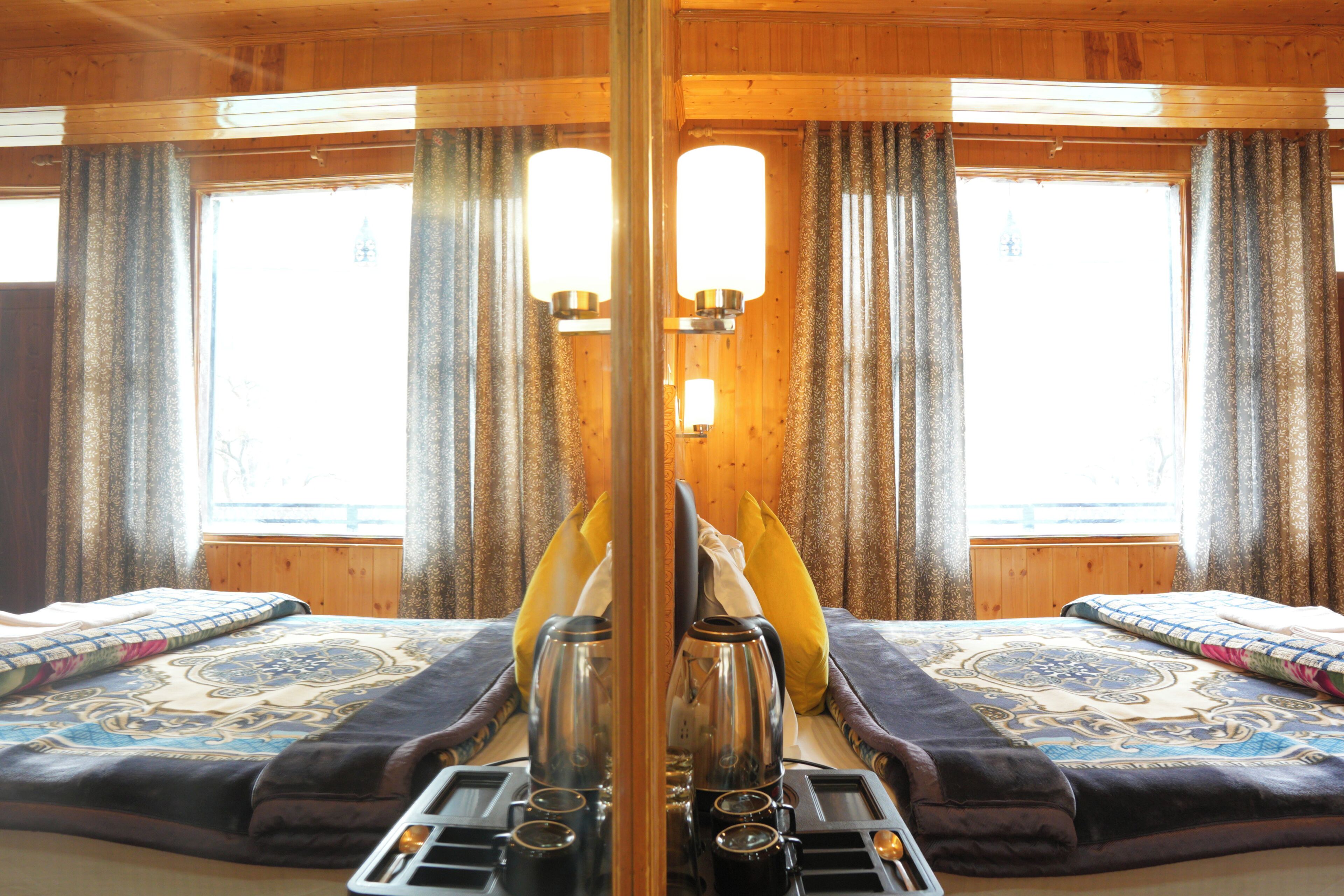Een kamer met een spiegel, een bed, een tafel met waterkoker, bekers en een dienblad.