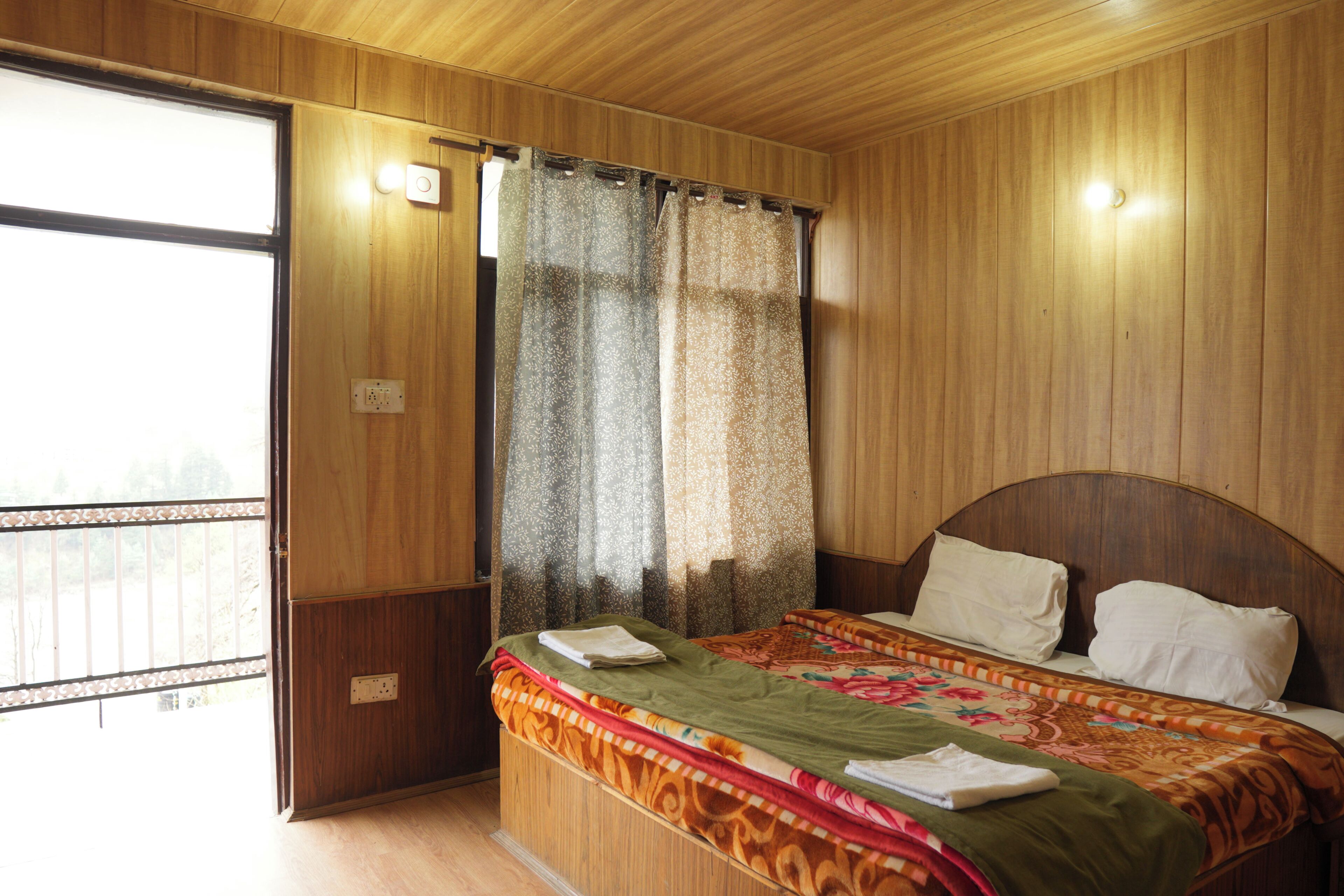 A wooden-paneled room with a bed, curtains, and a window.