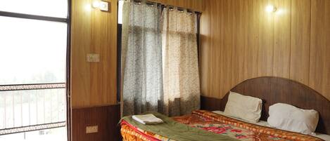 A wooden-paneled room with a bed, curtains, and a window.