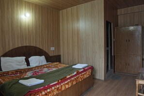 A room with a wooden headboard bed, a wardrobe, and a small table. - The himalayan Drift Cottage (Vashist)
