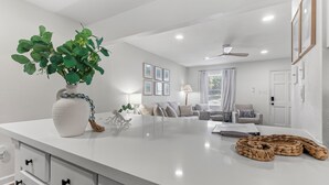 Una cocina moderna con una isla central, un rincón de comedor con un sofá y un ventilador de techo.