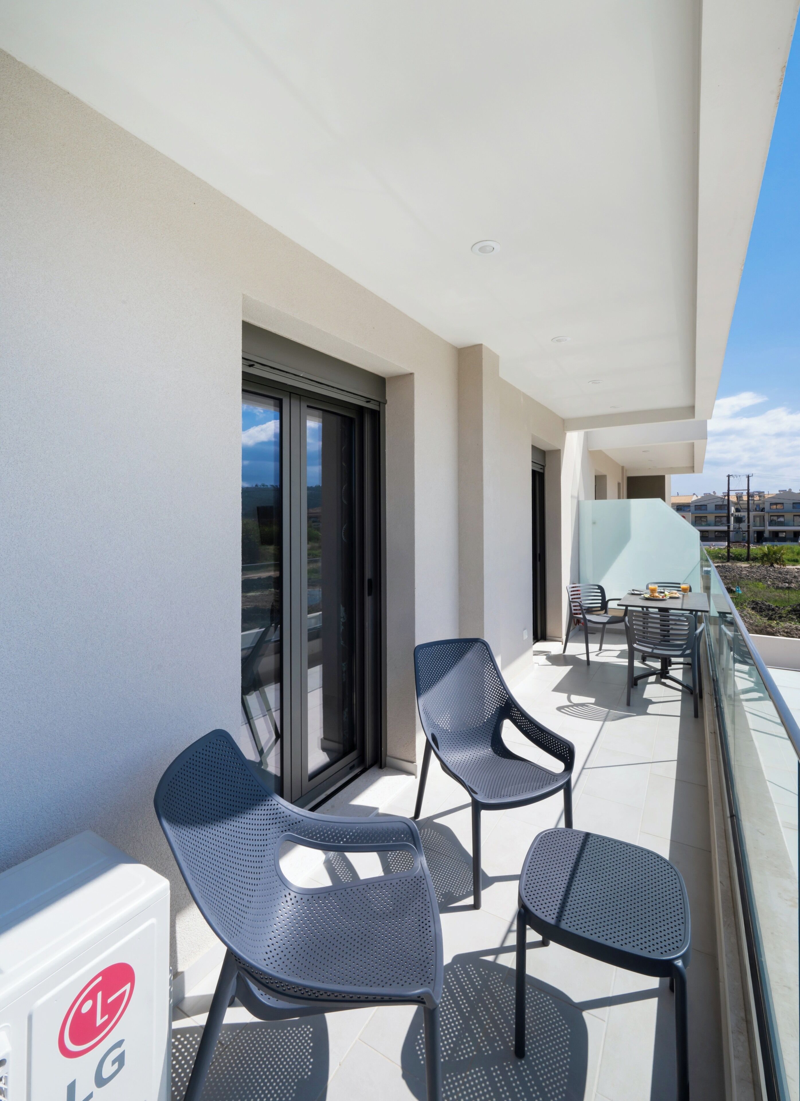 Ein Balkon mit zwei Stühlen, einem Tisch und einer Glastür, die zu einem Innenbereich führt.