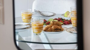 A breakfast table with a glass top, plates, cutlery, and a fruit bowl. - Urban Nest Collection Modern CityLiving  (Lefkada)
