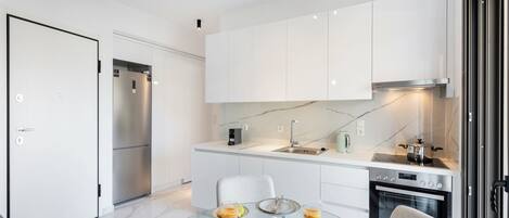 A modern kitchen with white cabinets, a built-in oven, and a dining area with a glass table set for breakfast.