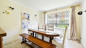 A dining area with a wooden table, benches, and a window with a metal grid. - bloomrooms - Knightsbridge (London)
