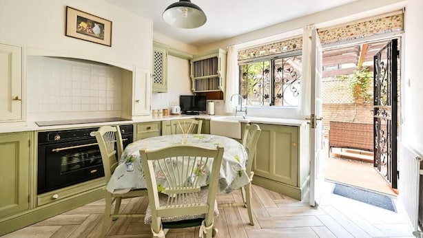 A kitchen with a dining table, chairs, and a view of the garden through an open door. - bloomrooms - Knightsbridge (London)