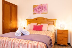 Ein Schlafzimmer mit einem Bett, einem Holzschrank, einem Nachttisch mit Lampe und einem Bild an der Wand.