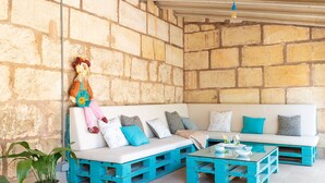 A rustic stone wall, a white sofa with teal accents, and a teal coffee table. - Pou de s'Alou by Rentallorca (Sineu)
