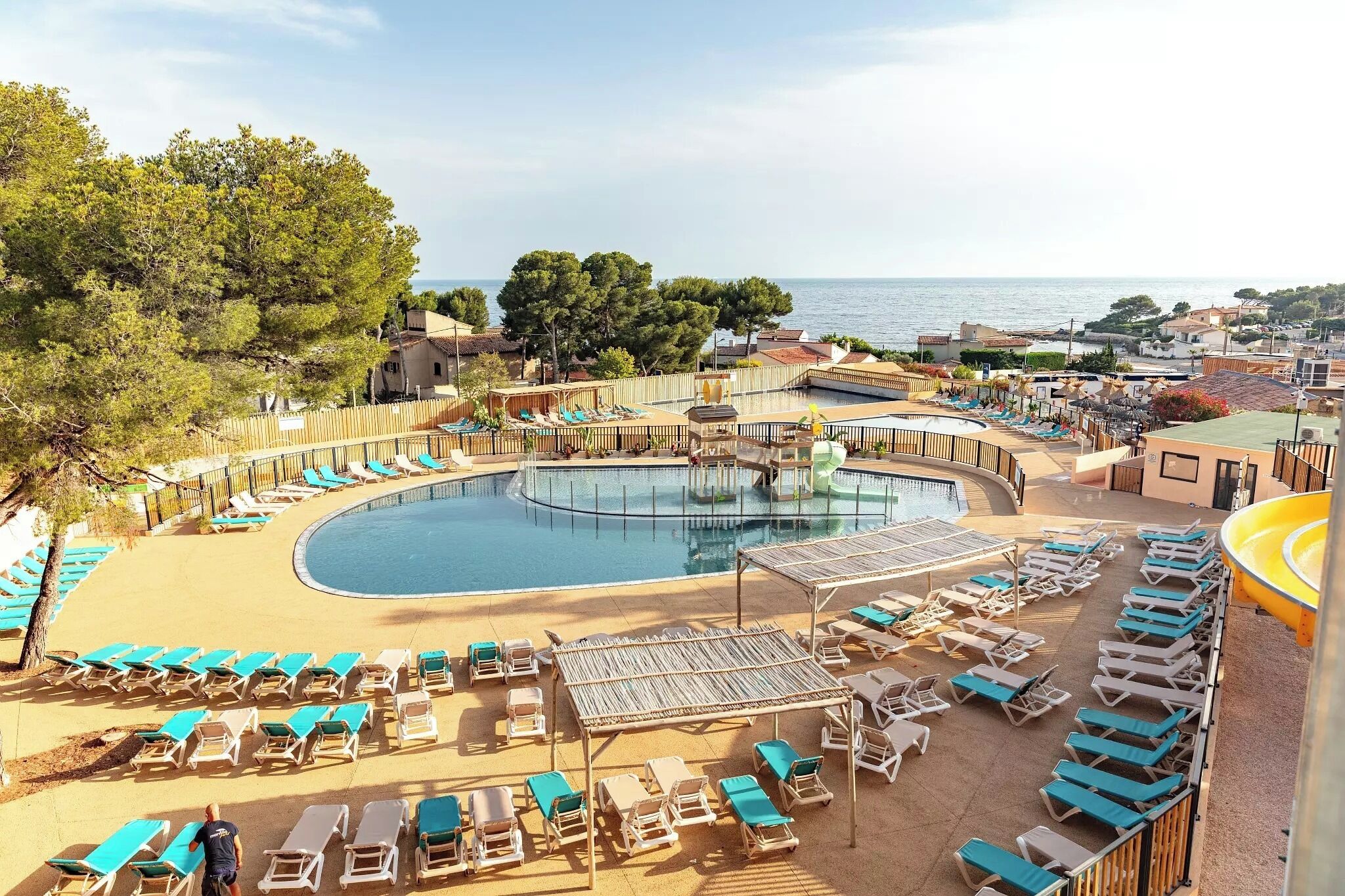 A pool area with lounge chairs, a circular pool, and a view of the sea.