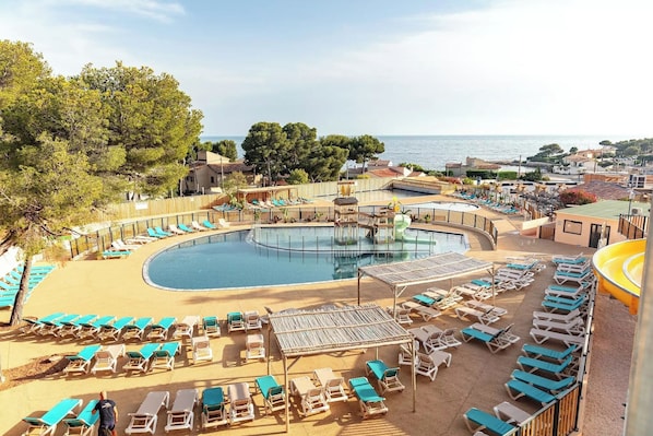 A pool area with lounge chairs, a circular pool, and a view of the sea. - Premium Mobile Home for 6 People 4-Star Beach Access – Pool & Air Conditioning (Carry-le-Rouet)