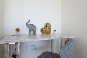 Une table en marbre ornée d’une petite figurine d’éléphant, d’un objet en forme de cœur doré et d’une plante en pot.