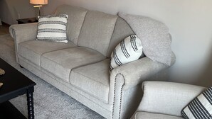 A living room with a grey sofa, two matching armchairs, a black coffee table, a floor lamp, and a framed picture on the wall. - Executive home in Private HOA near Amusement Parks. 2 Master Bedrooms - Sleeps 6 (Waterloo)