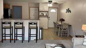 A living room with a black coffee table, a grey sofa, a ceiling fan, and a kitchen area in the background. - Executive home in Private HOA near Amusement Parks. 2 Master Bedrooms - Sleeps 6 (Waterloo)
