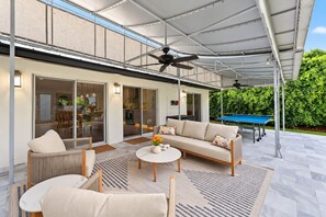 Ein Außenbereich mit Terrasse, einer Couch, Sesseln, einem Couchtisch und einem Billardtisch.