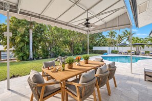 An outdoor patio with a pool, surrounded by lush greenery and palm trees. - Direct Lake Ida Access | Sleeps 8 | Golf Cart | Heated Pool | by Delray Nightly (Boynton Beach)